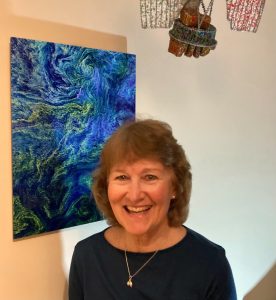 Picture of Venetia Stuart standing in front of a framed ocean colour image and beside a beaded version of the Coastal Zone Color Scanner